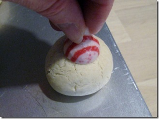pressing peppermint kiss into a cookie