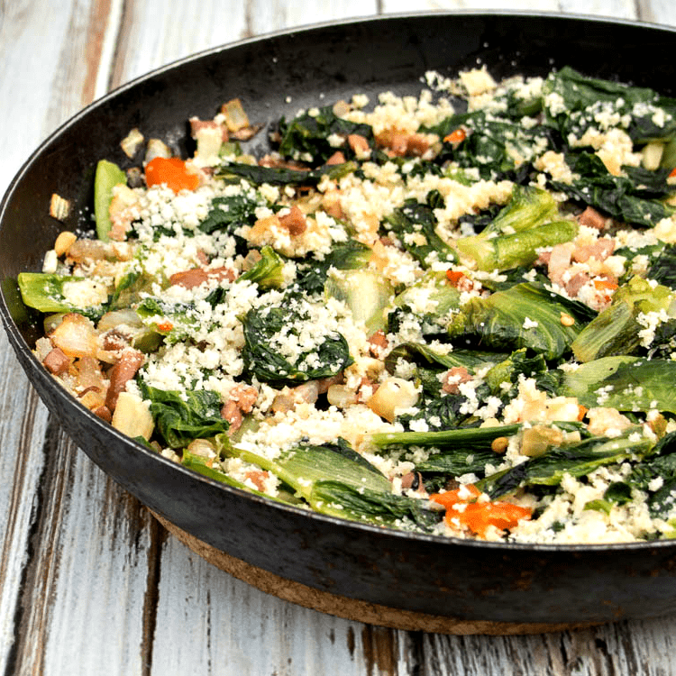 A skillet filled with spinach and ham.