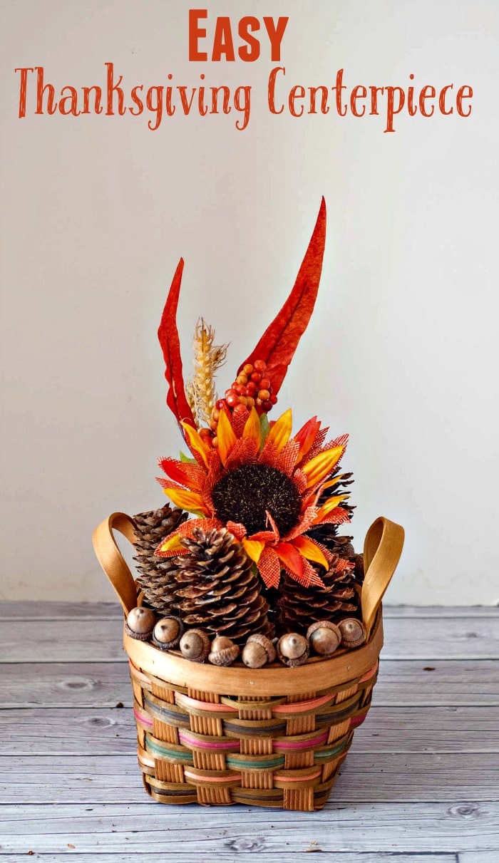 Easy Thanksgiving Centerpiece - a simple basket filled with pine cones and lined with acorns is finished off with a sunflower floral spray.
