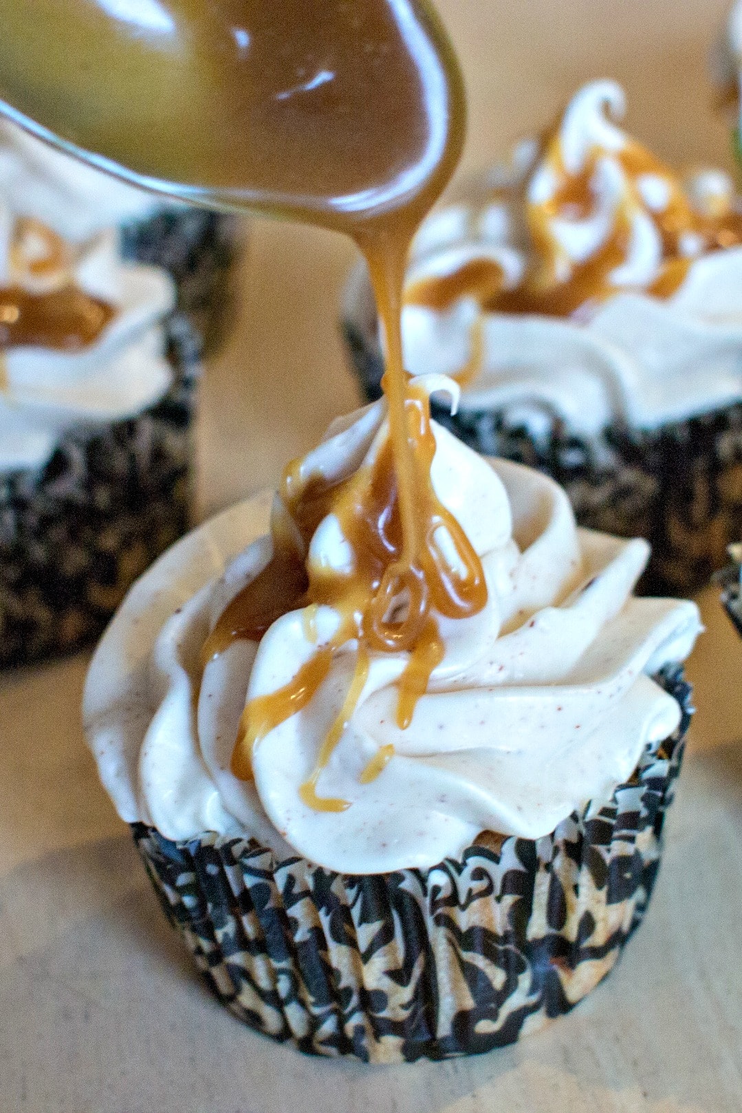 Drizzling Caramel sauce on apple spice cupcakes