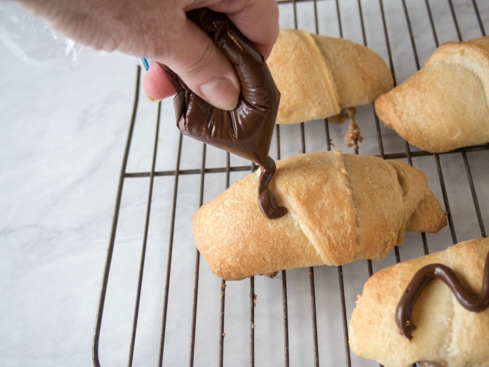 Drizzling chocolate on top of crescent roll desserts