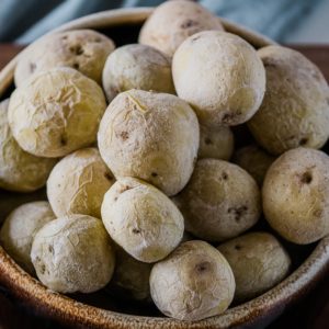 Frozen potatoes in a bowl on a wooden table.