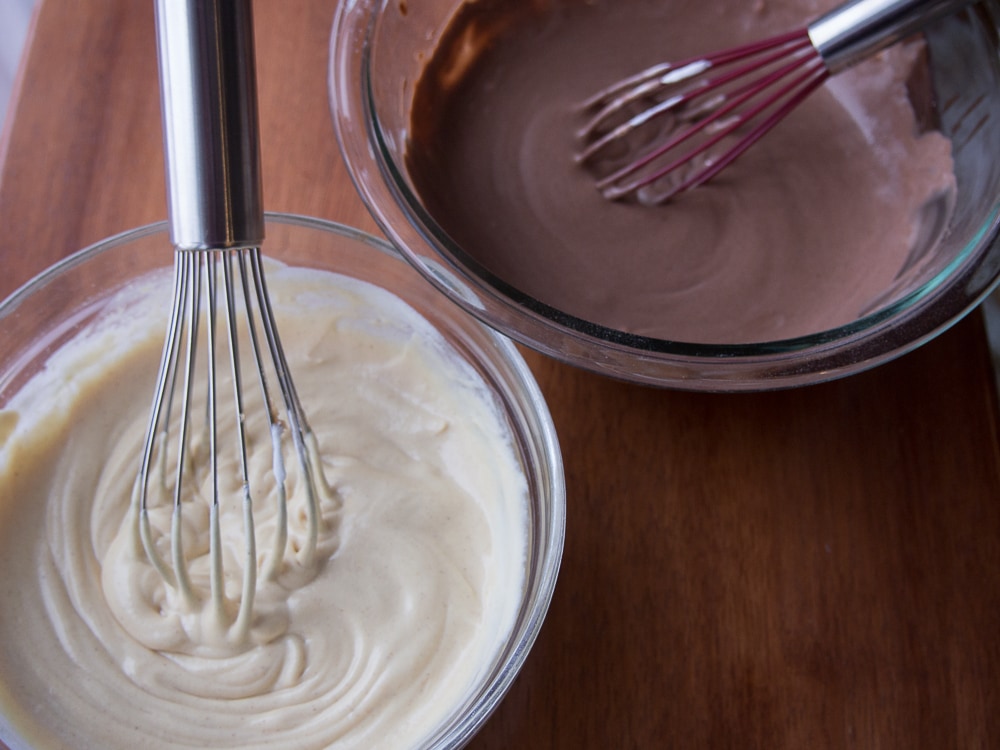 Two bowls of batter with a whisk in them.