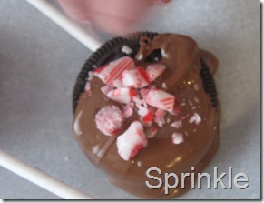 Sprinkling crushed candy canes on chocolate covered oreos