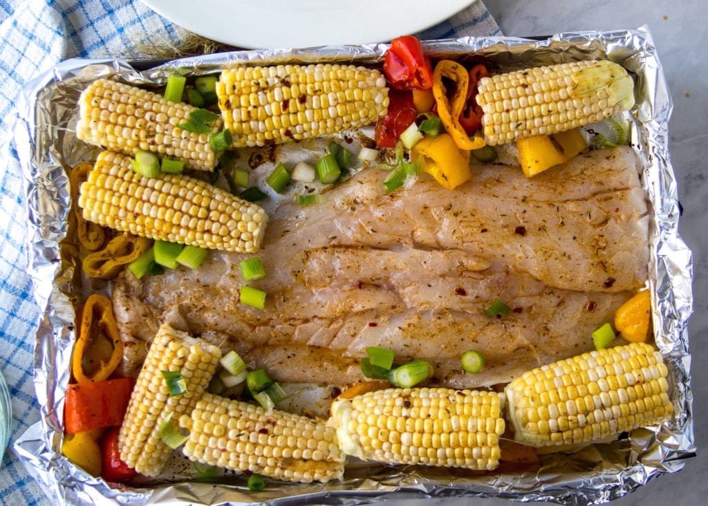 fish and veggies on sheet pan before cooking