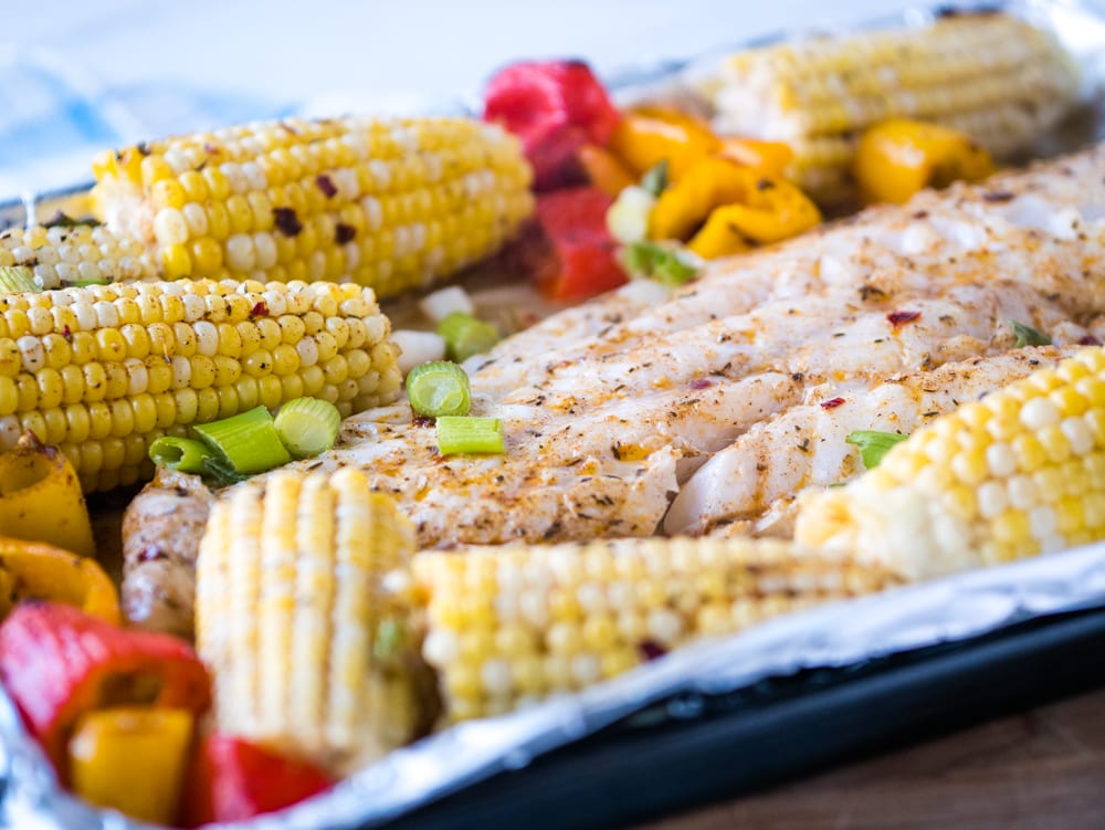 closeup view of cod cooked iwth Caribbean seasonings with corn and bell peppers