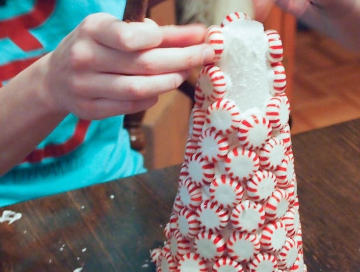 A girl is making a candy cane christmas tree.