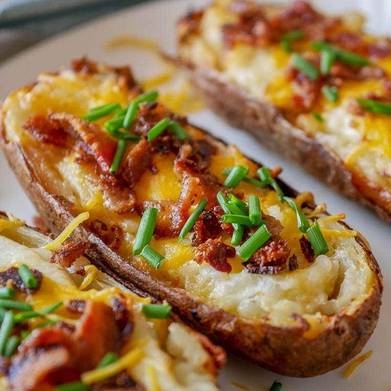 close up view of an air fryer twice baked potato with cheese, bacon and chives