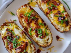 potatoes on a plate with cheese, bacon and chives