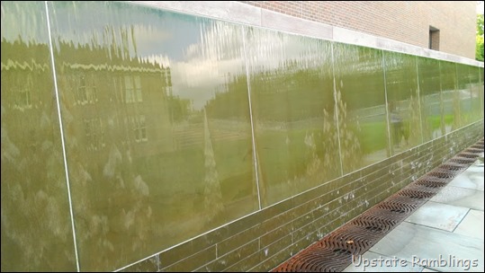 A green wall with a reflection of a building.