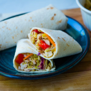 chicken wrap cut in half on a plate with another wrap in the background