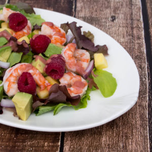 A salad with shrimp, avocado and raspberries.