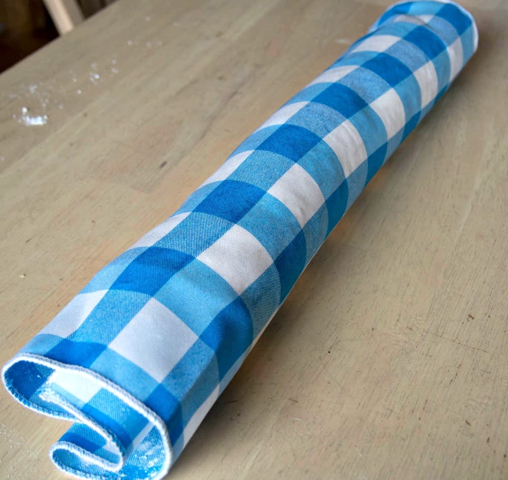 A blue and white checkered strawberry roll on a wooden table.
