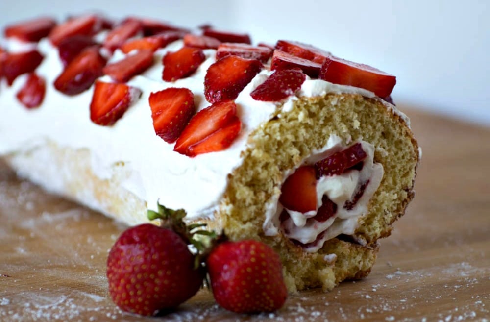 A strawberry roll cake with whipped cream and strawberries.