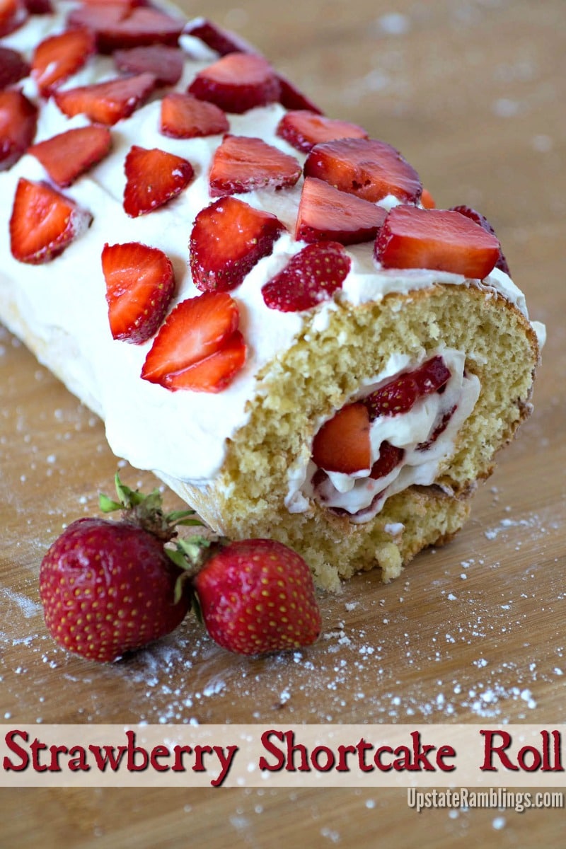 Strawberry roll cake on a wooden cutting board.