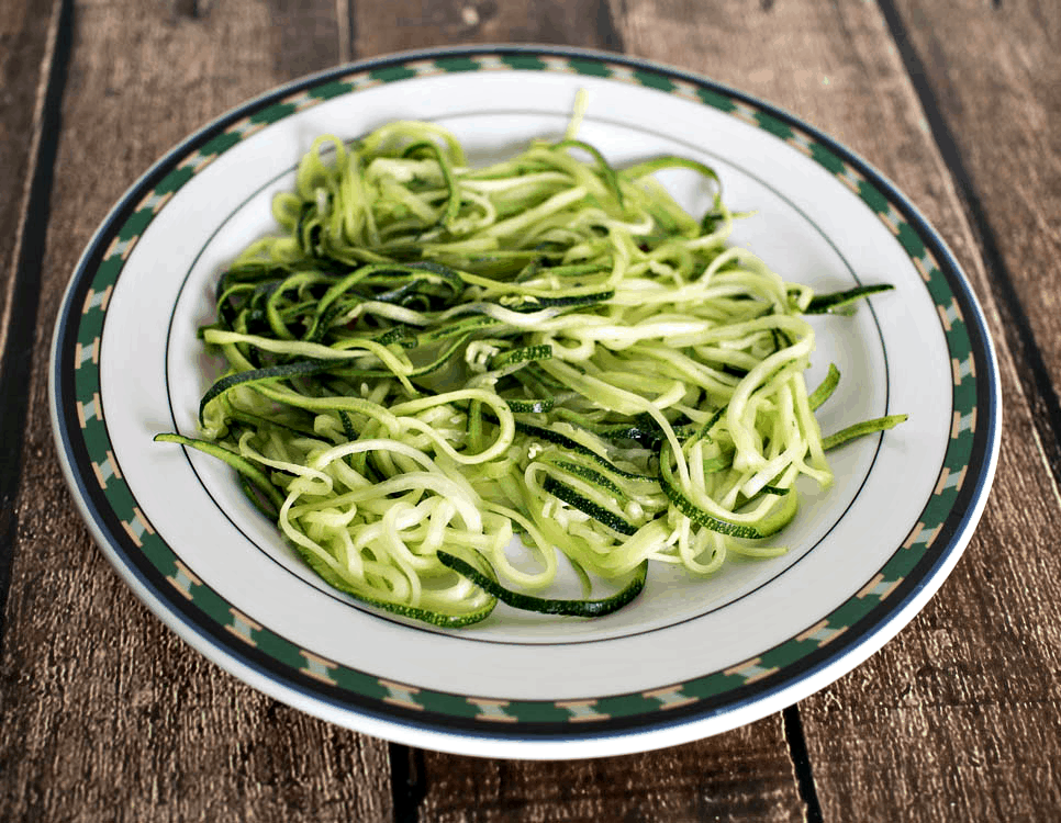 Zucchini noodles on a plate on a wooden table.