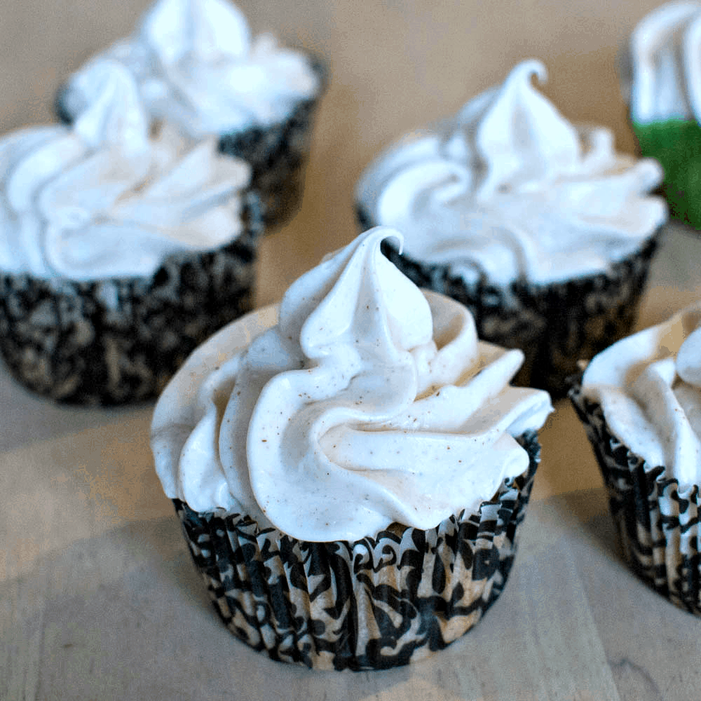 A group of cupcakes with whipped cream on top.