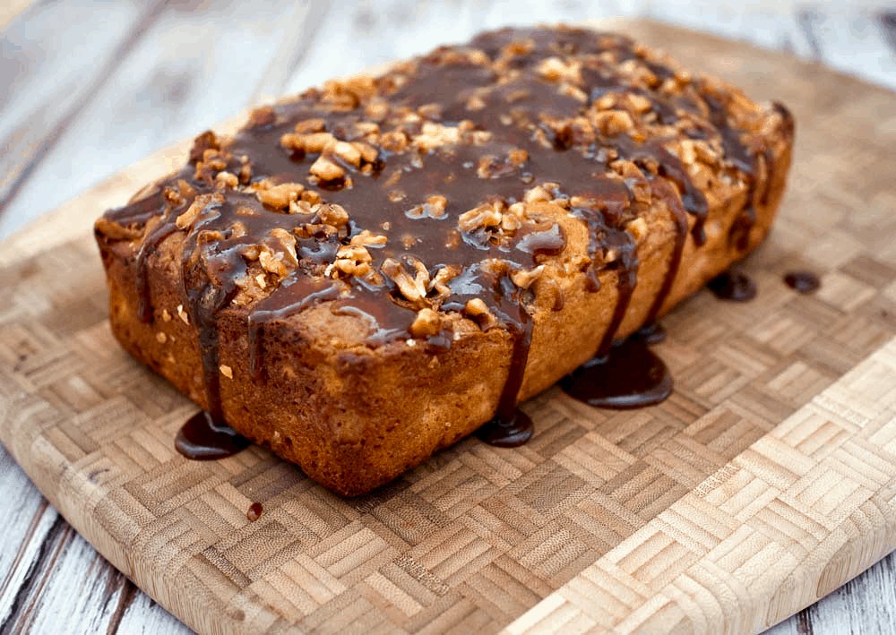A slice of apple bread with caramel sauce on a cutting board.