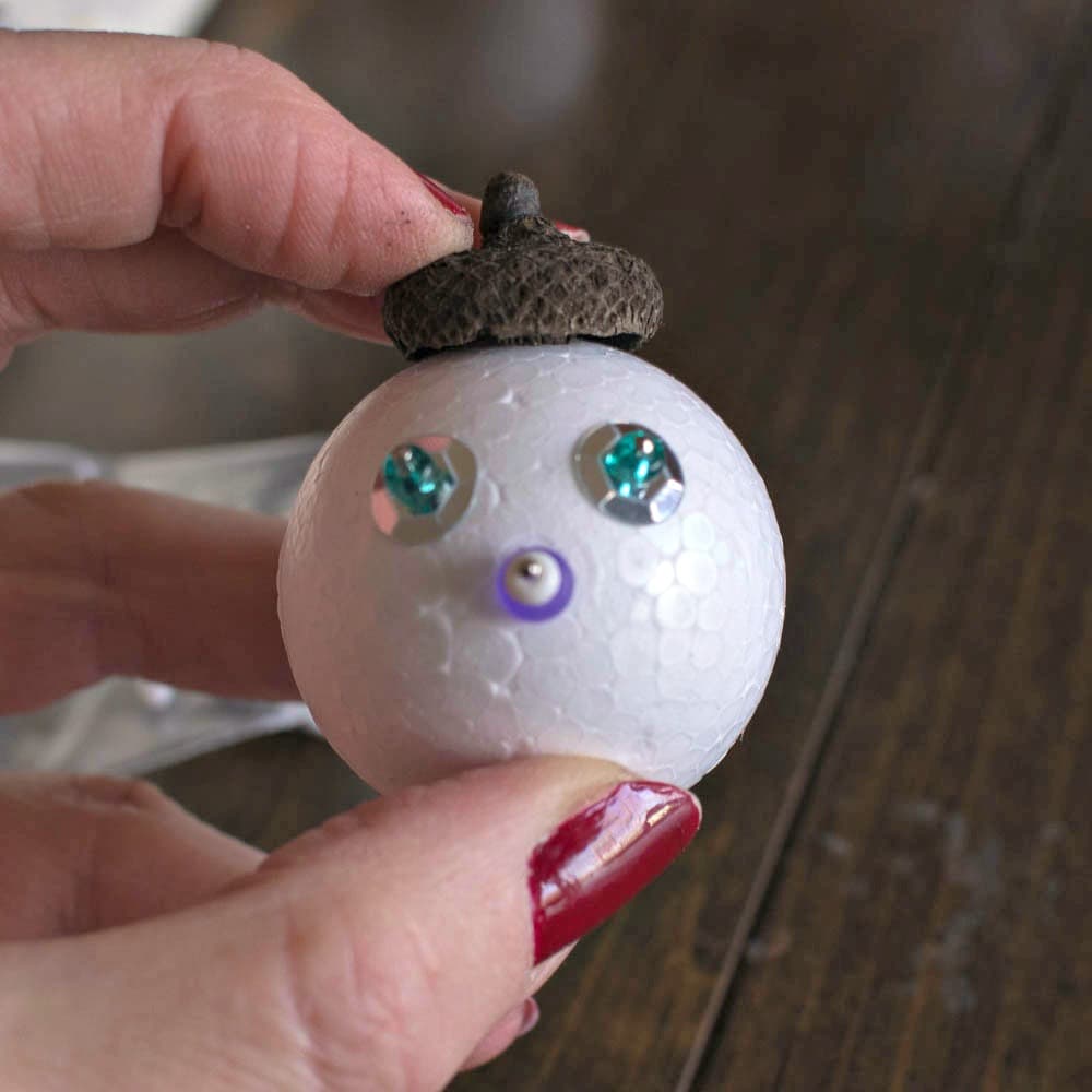 A person holding a snowman ornament.