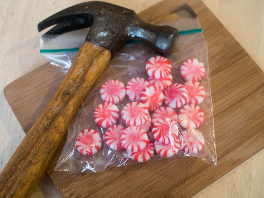 A hammer and candy canes on a cutting board.