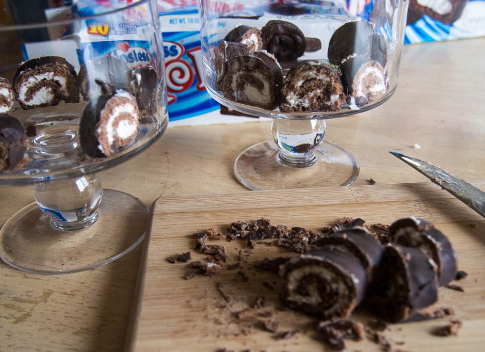 Two glasses of chocolate roll ups on a cutting board.