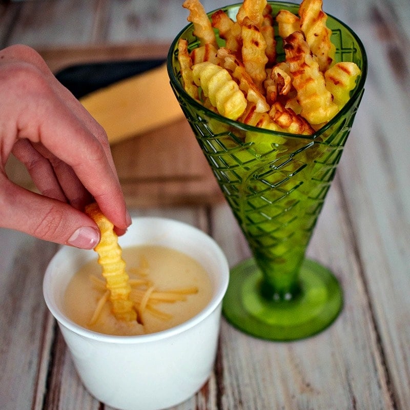 Dipping french fries into Gouda cheese sauce - football party