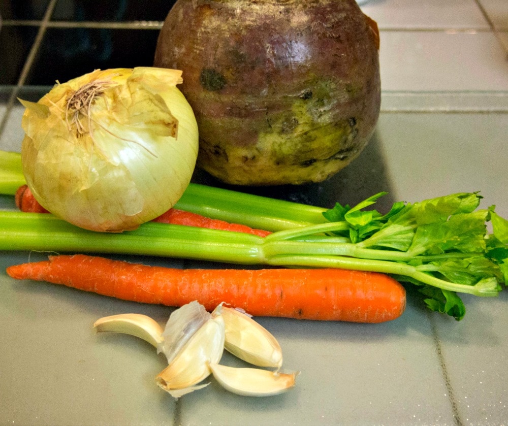 Carrots, celery and garlic on a kitchen counter.