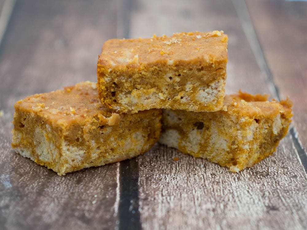 Three squares of white chocolate pumpkin bars stacked on top of each other.