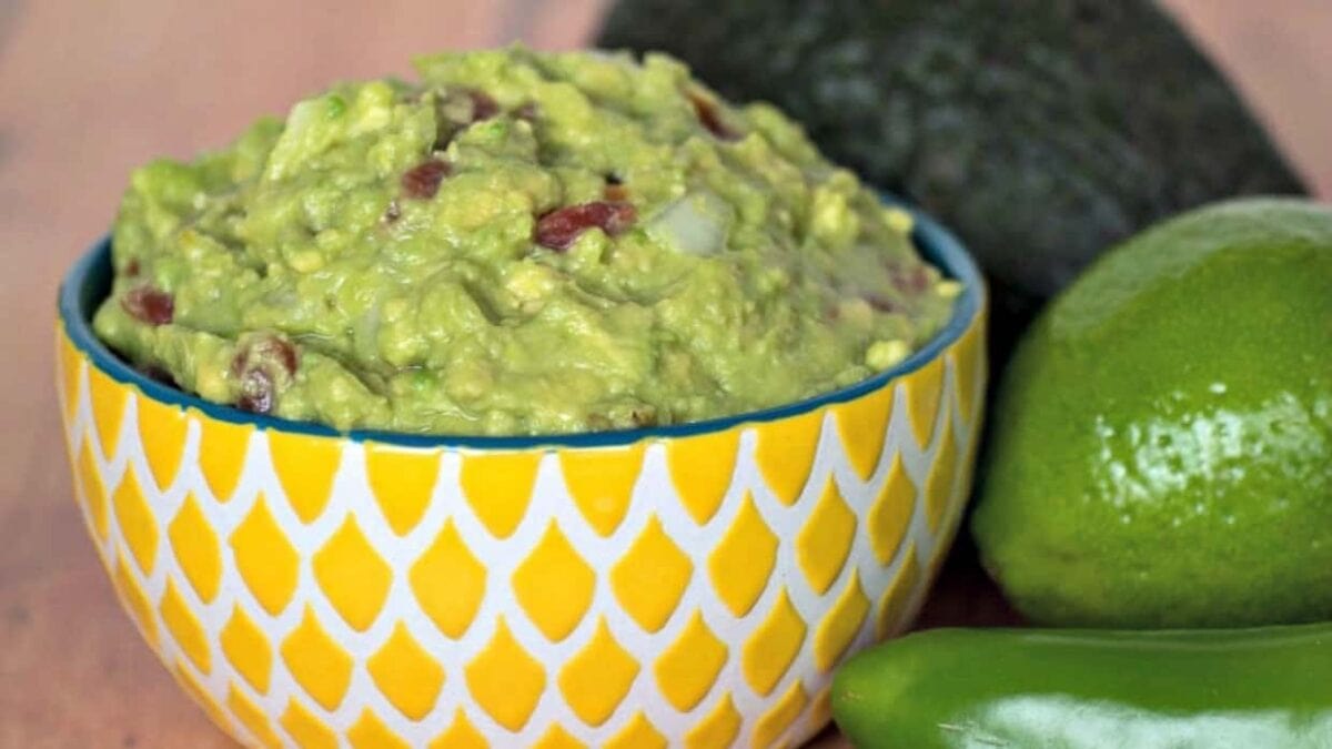 Yellow bowl with guacamole and avocados.