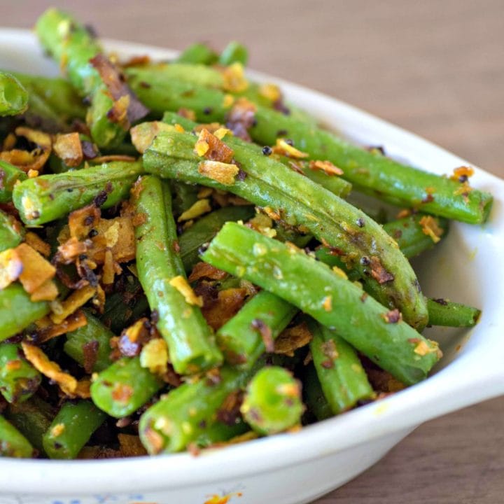 Sauteed green beans in a white bowl.