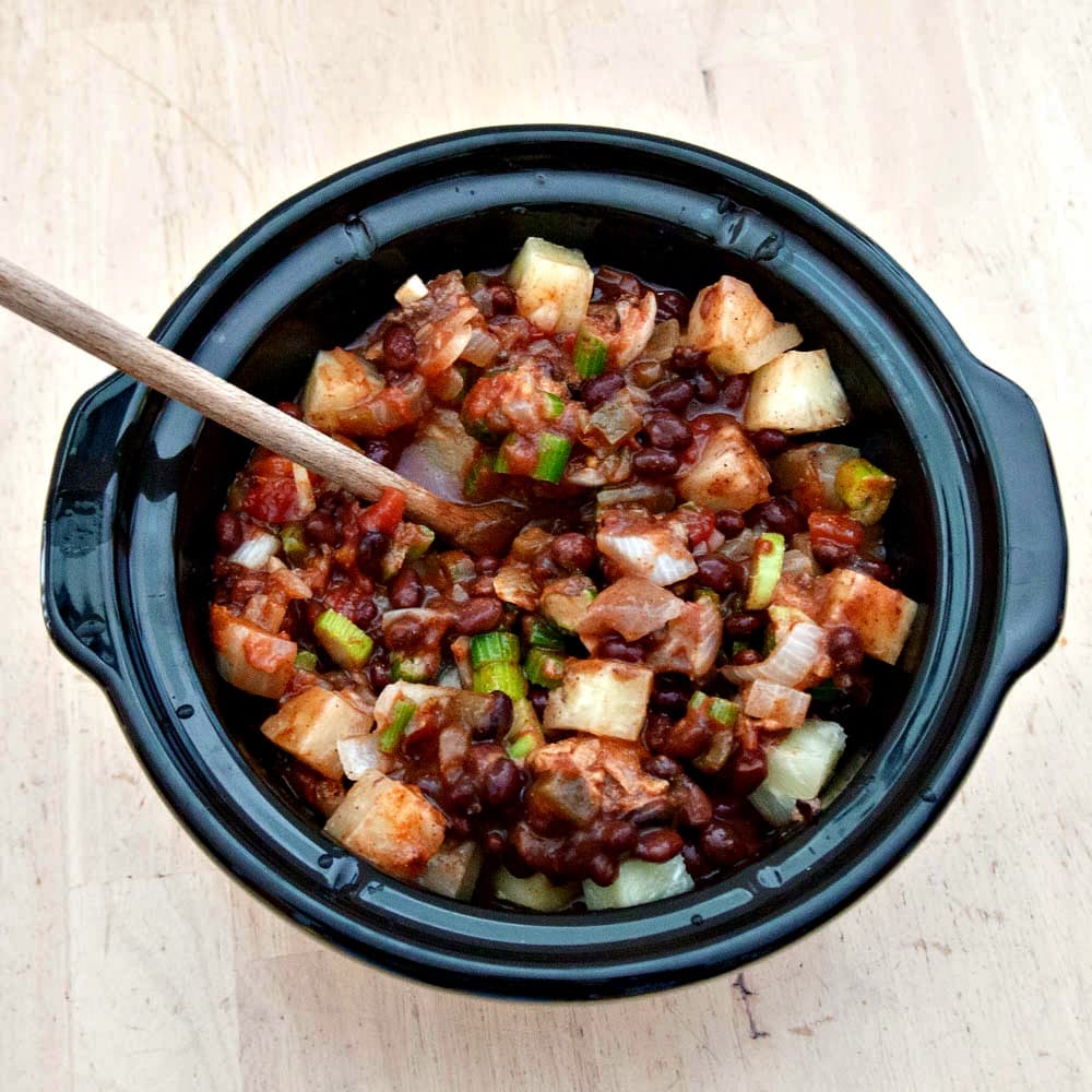 A bowl of Slow Cooker Hawaiian Chili with a wooden spoon.