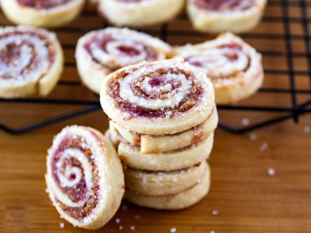 stack of raspberry pinwheel cookies in front of a baking rack