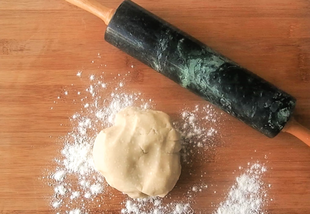 ball of dough on a cutting board with flour and a rolling pin