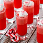 Candy cane shot glasses with whipped cream and candy canes.