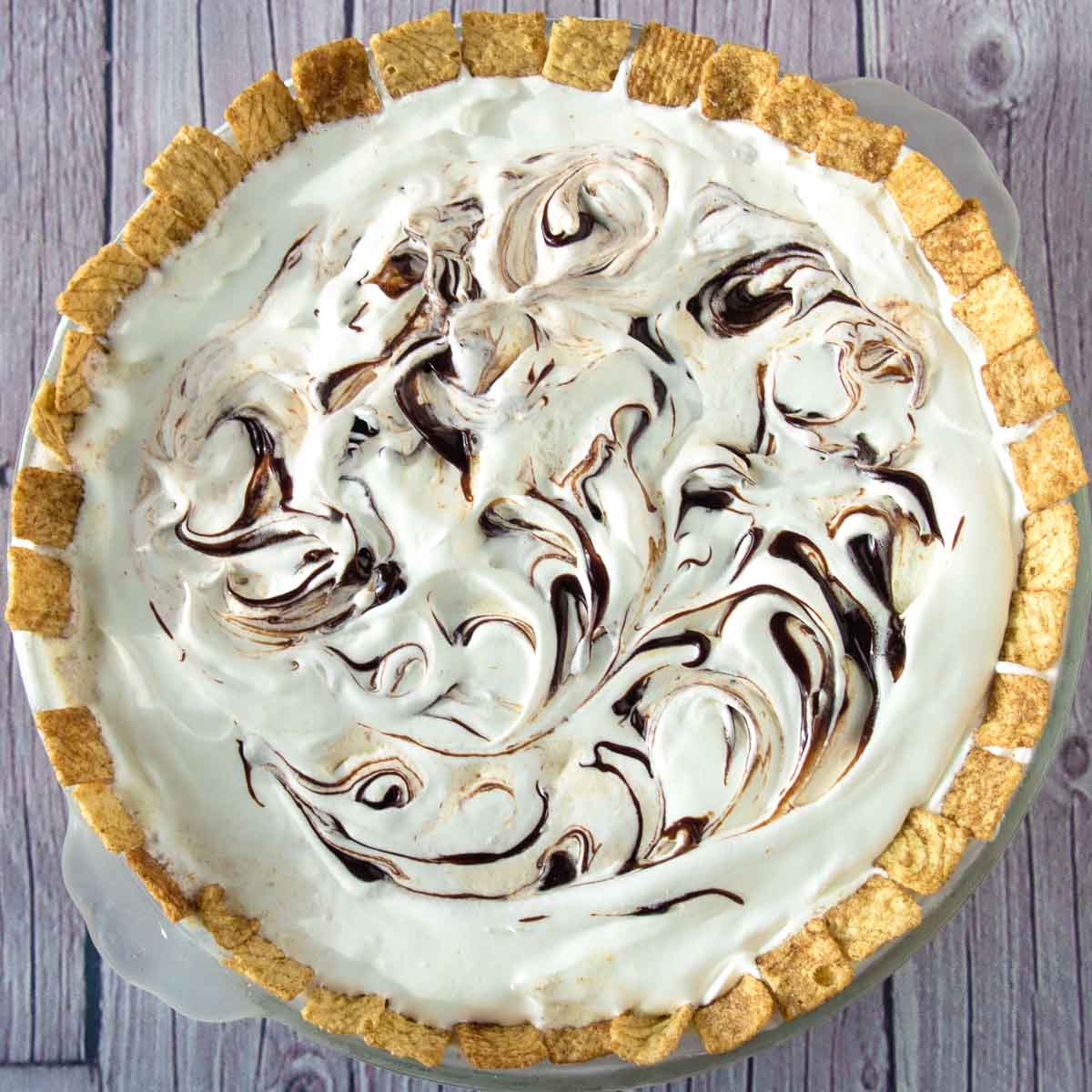 Ice cream pie with swirls of hot fudge on top and cinnamon cereal around the edges.
