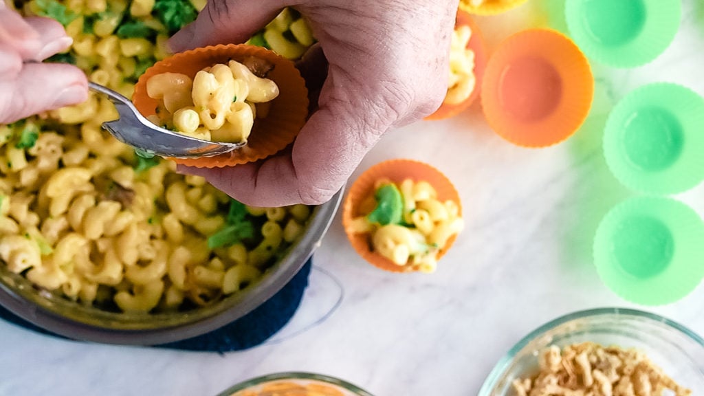 spooning mac and cheese into the silicon muffin cups