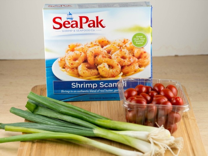 Seapak shrimp scramble with tomatoes and onions on a cutting board.