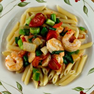 A plate of pasta with shrimp and tomatoes.