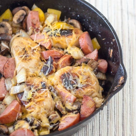 A skillet filled with sausage, mushrooms and onions.