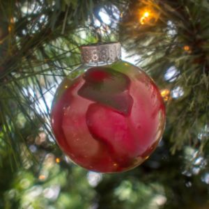 A vibrant melted crayon ornament hanging on a Christmas tree.