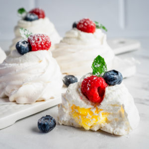 mini pavlova with lemon curd and berries on a cutting board