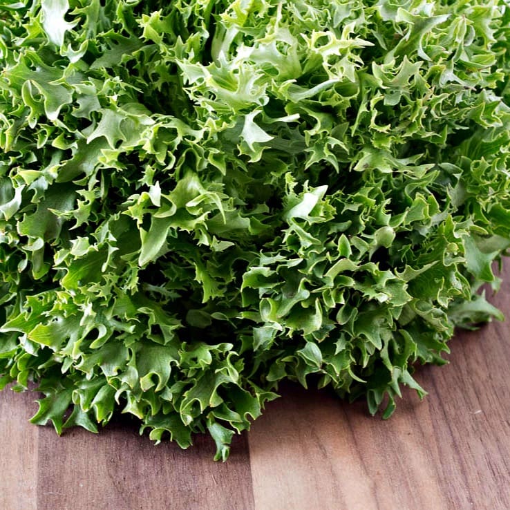 A bunch of arugula on a wooden table.