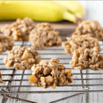Oatmeal cookies on a cooling rack next to bananas.