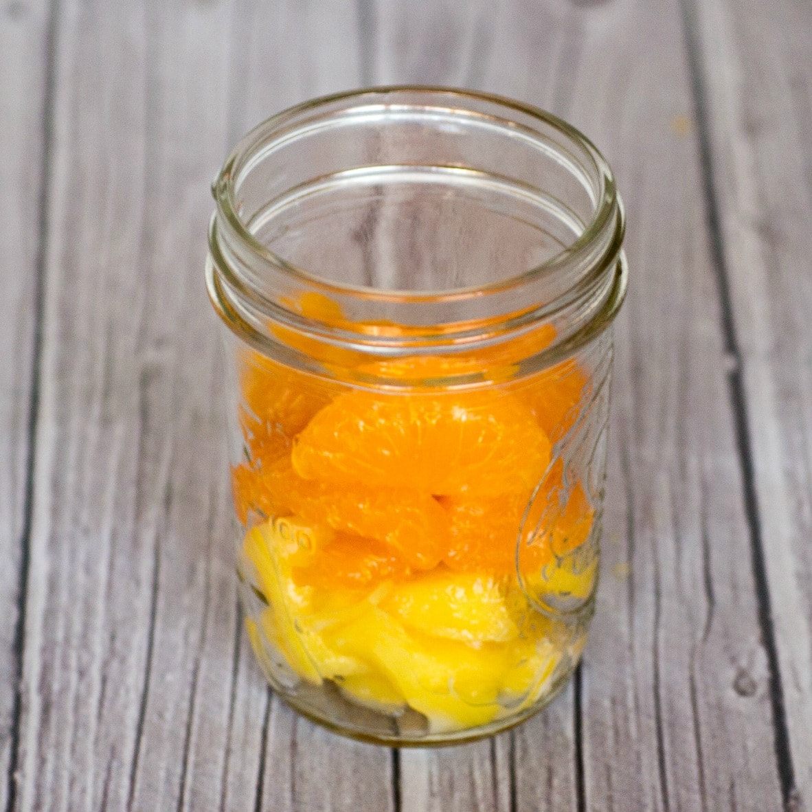 Mango and Mandarin oranges layered in a Mason jar for Fruit and Yogurt Parfait