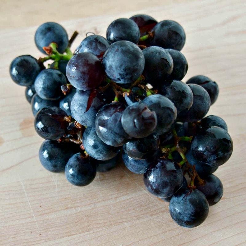 bunch of Concord grapes on a cutting board