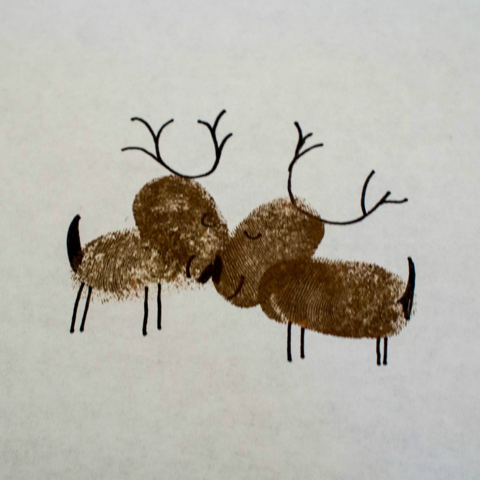 Two reindeer are kissing on a piece of paper.