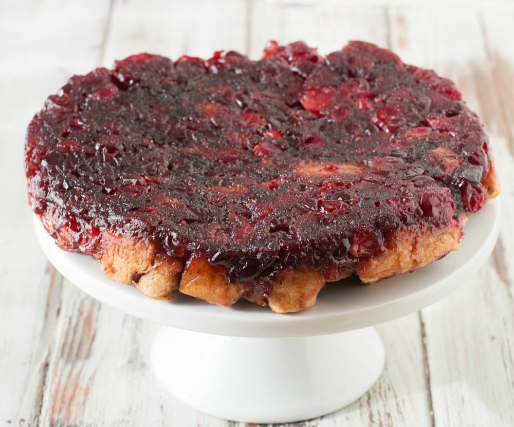 This upside down Cranberry Cinnamon Roll Cake on a cake stand