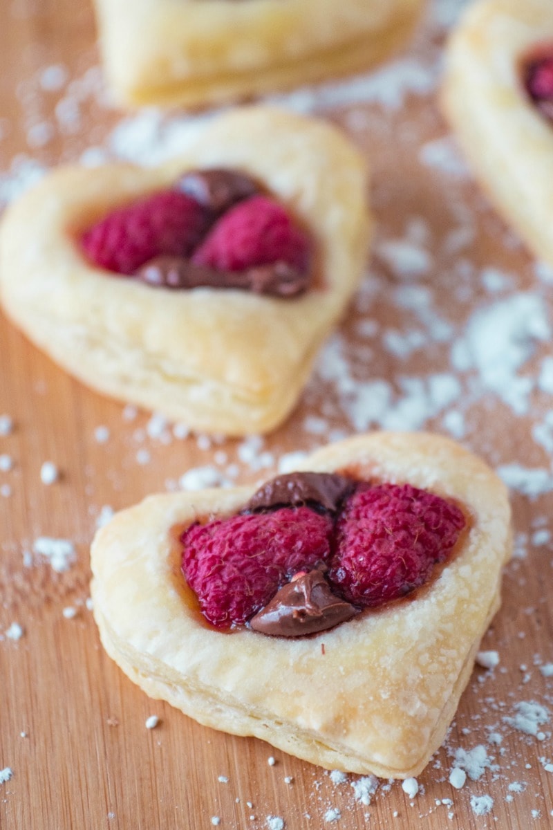 These Valentine Puff Pastry Cookies are super easy to make, and perfect for Valentine's Day! Puff pastry is cut into hearts and topped with creamy Nutella and raspberries then baked until golden brown for a sweet and flaky cookie that is ready in minutes. Only three ingredients! #cookies #hearts #nutella #valentinesday
