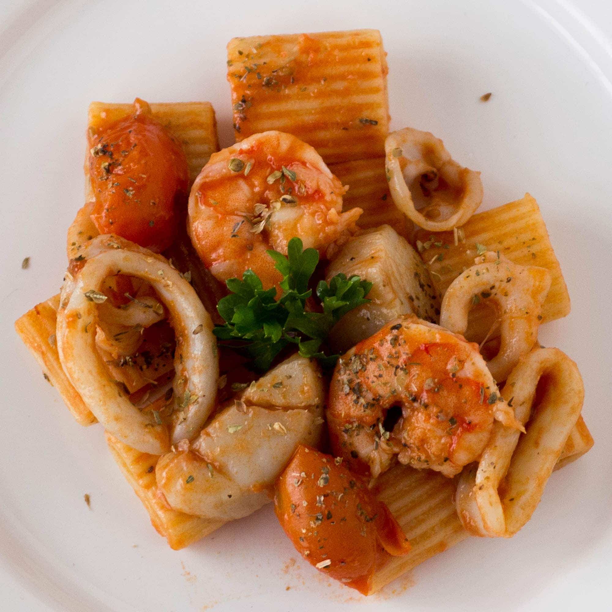 A plate of pasta with shrimp, tomatoes and parsley.