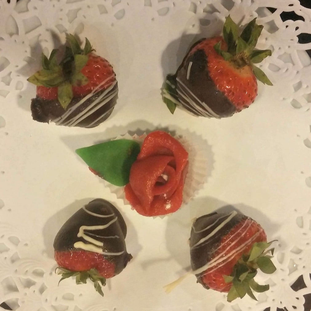 Four chocolate covered strawberries on a white plate.